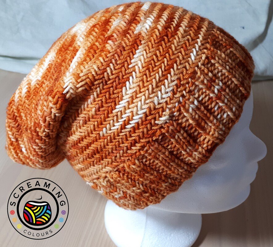 Gestrickte orange Beanie mit Zickzackmuster auf weißem Schaufensterkopf
