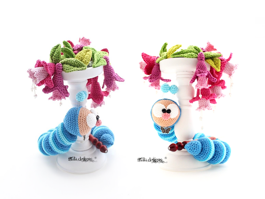 Gehäkelte blau-gestreifte Raupe mit rosa Häkelblüten an weißem Ständer