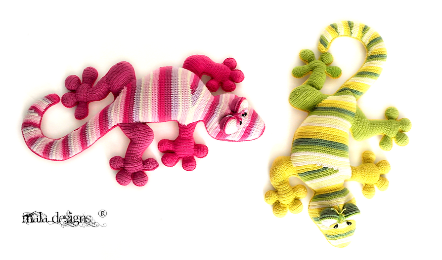 Zwei bunte Amigurumi-Eidechsen, gestreift in Rosa/Pink und Gelb/Grün, liegend