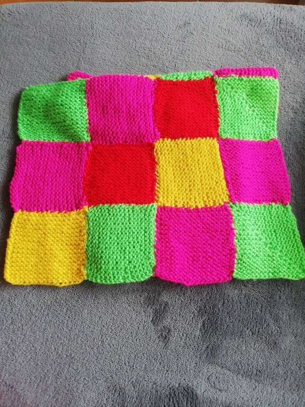 Patchwork-Babydecke aus leuchtenden Quadraten in Pink, Grün, Gelb und Rot