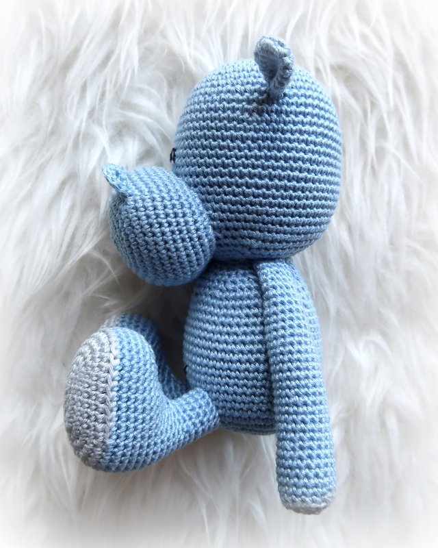 Hellblaues gehäkeltes Amigurumi-Wasserbewohner auf weißem Fell, Seitenansicht