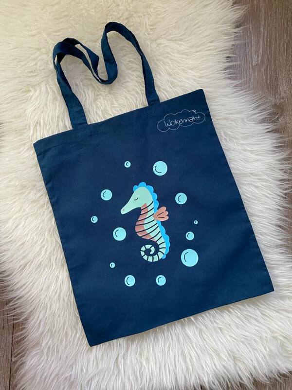 Dunkelblauer Stoffbeutel mit buntem Seepferdchen-Plot und mehreren hellblauen Blasen auf hellem Hintergrund
