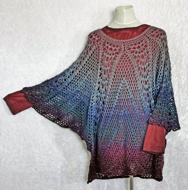 Gehäkelter Damenponcho in Farbverlauf von Grau zu Burgunderrot mit offenem Lochmuster auf einer Schneiderpuppe.
