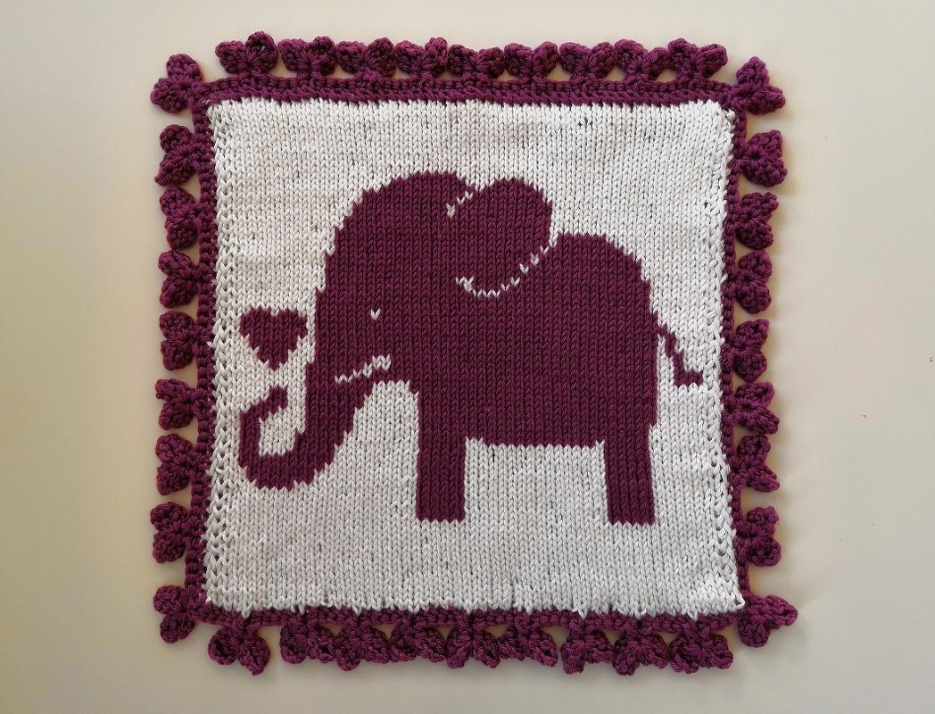 Quadratisches Strickstück in Weiß und Dunkelviolett mit Elefantenmotiv und dekorativem Rand