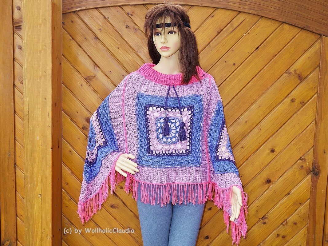 Mannequin trägt gehäkelten Poncho mit großen Granny
Squares, geripptem Kragen, Kordel und pinken Fransen