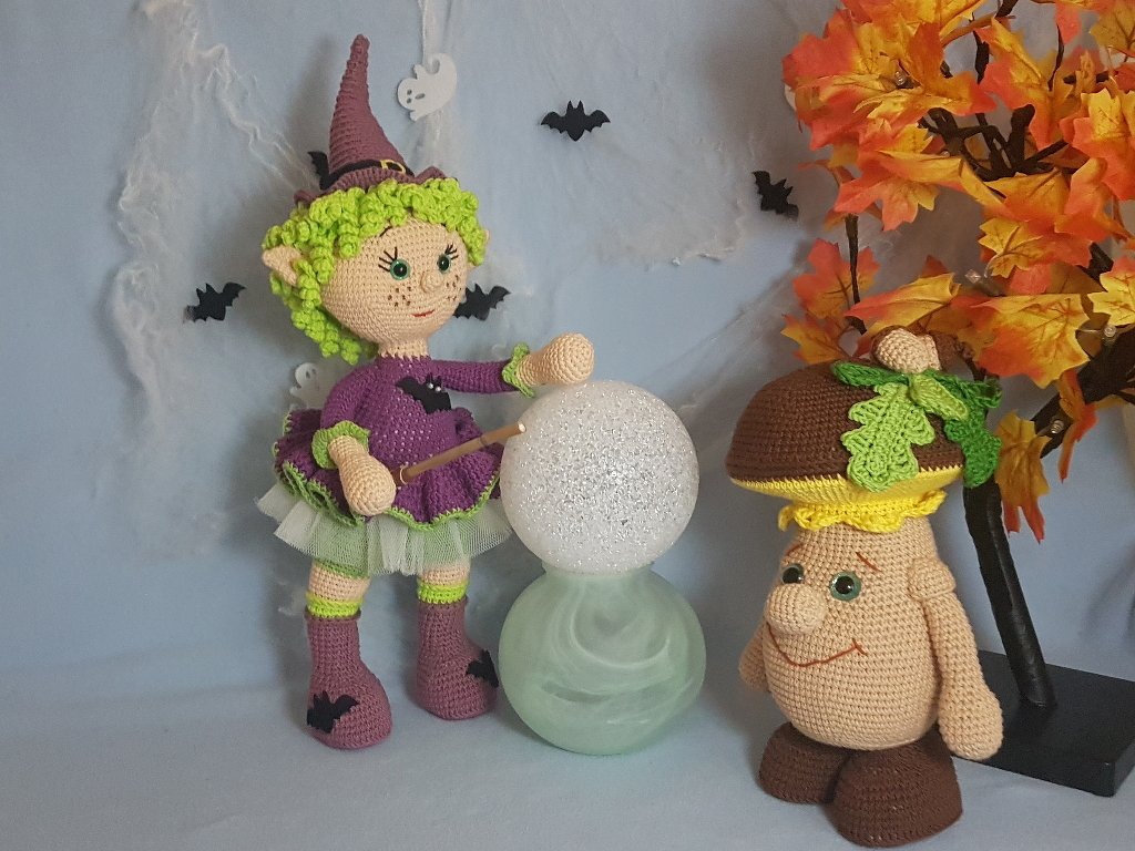 Amigurumi-Hexe in Lila neben einer gehäkelten Pilzfigur mit grüner Blattapplikation