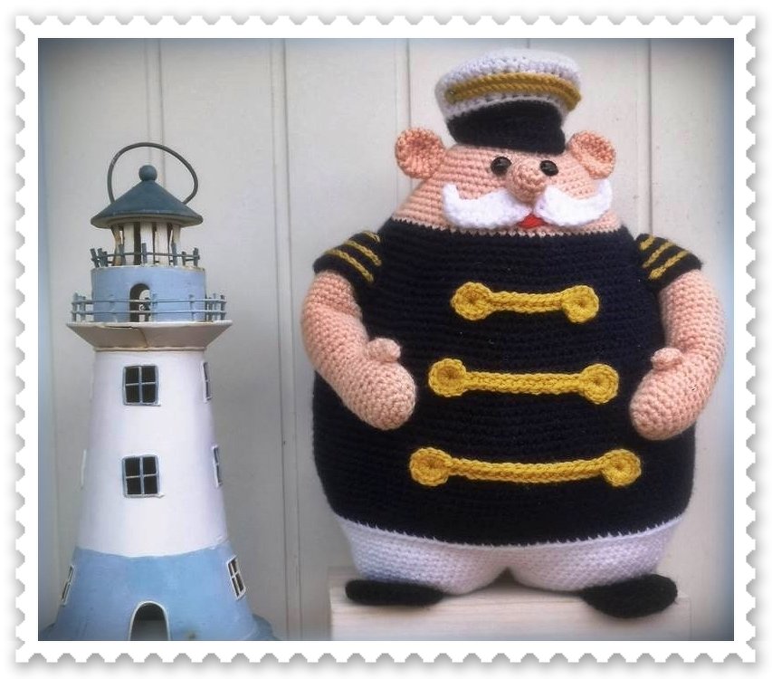 Gehäkelte Kapitänsfigur in schwarzer Uniform neben Modell-Leuchtturm