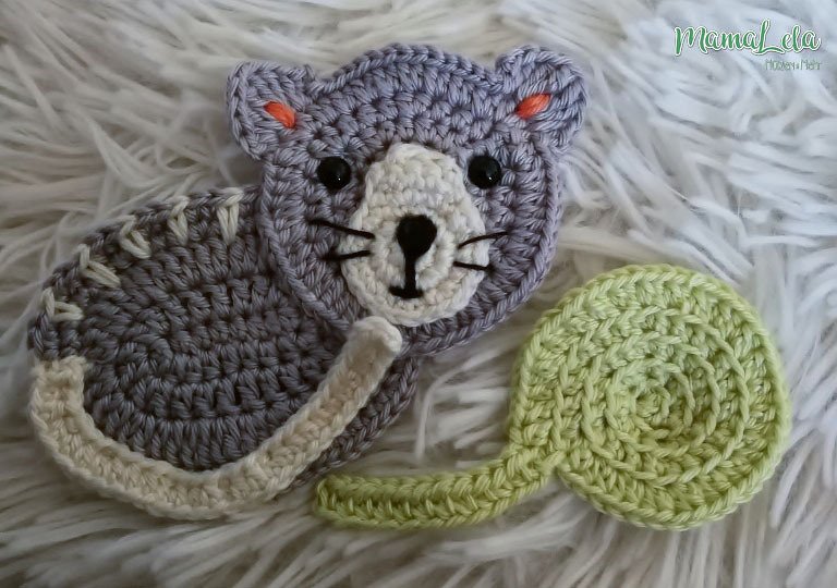 Schnell gehäkelte Tier-Applikationen: graue Katze und grüne Spirale auf weißem Fellstoff