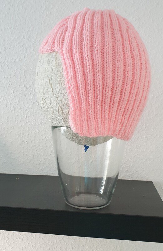Rosa gestrickte Mütze mit vertikalem Rippenmuster auf hellem Kopfmodell