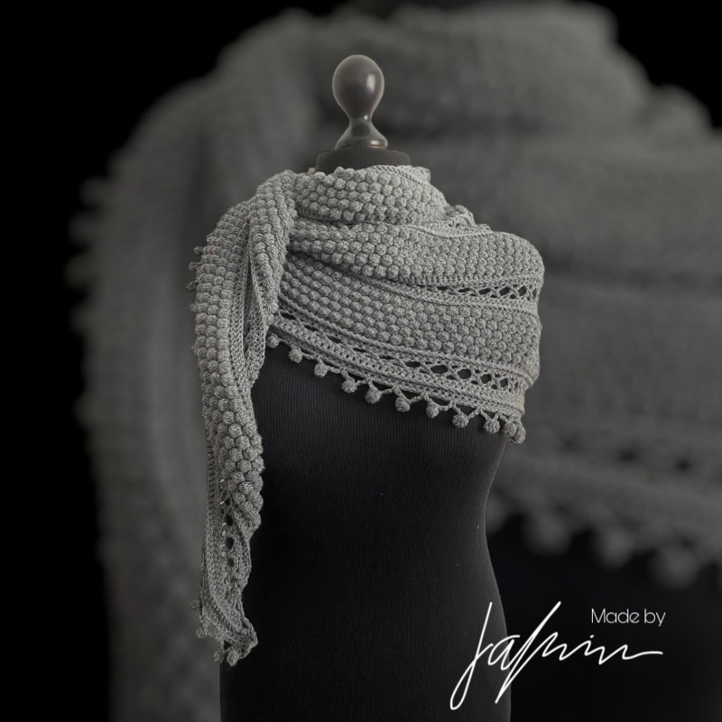 Grey crochet triangle shawl with bobble rows on black mannequin