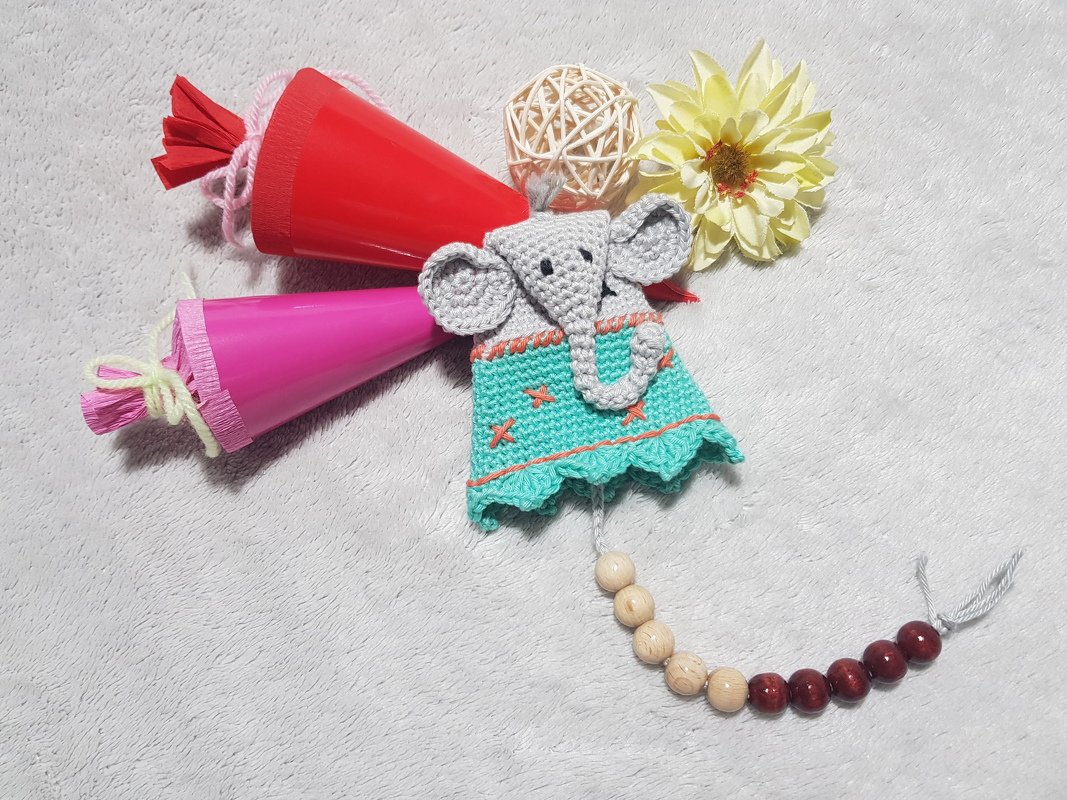 Gehäkelte Elefantenpuppe in Grau und Türkis mit Holzperlenkette, daneben zwei kleine Schultüten und eine Dekoblume