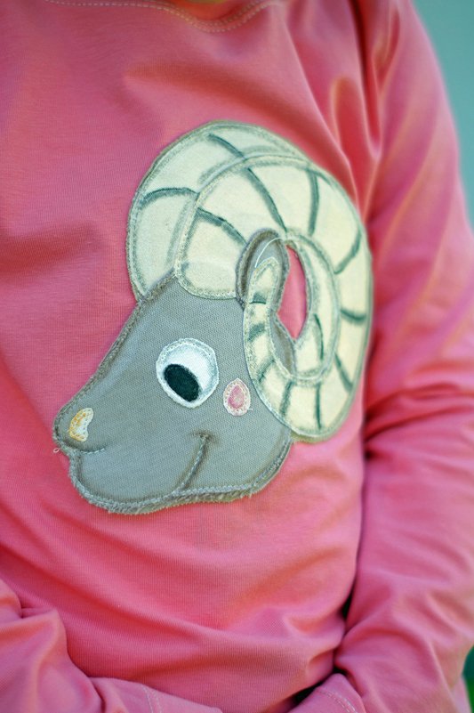 Mehrlagige Widder-Applikation mit sichtbaren Nähten auf rosa Stoff