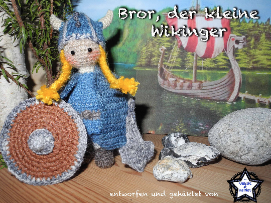 Gehäkelte Amigurumi-Wikingerpuppe mit blonden Zöpfen, blauem Helm, blauem Kleid, rundem Schild und kleinem Hammer vor gemaltem Wikingerschiff