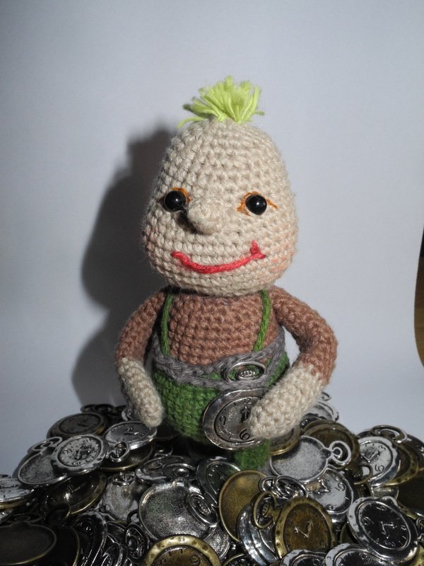 Gehäkelte Amigurumi-Puppe mit grünem Haar und Latzhose auf Uhranhängern
