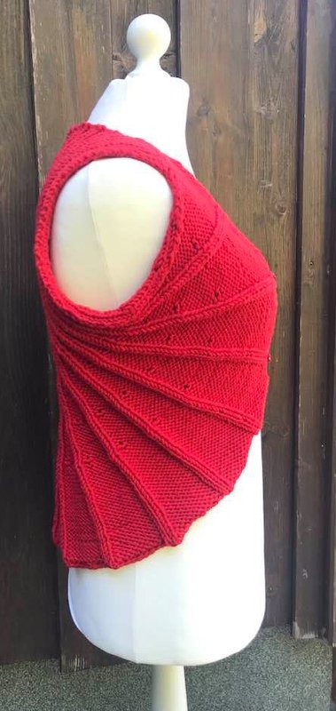 Mannequin trägt asymmetrische rote Strickweste mit spiralförmigen Falten