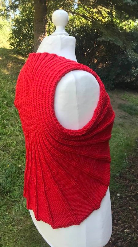 Rote gestrickte Damenweste mit asymmetrischem Saum auf Schaufensterpuppe im Garten
