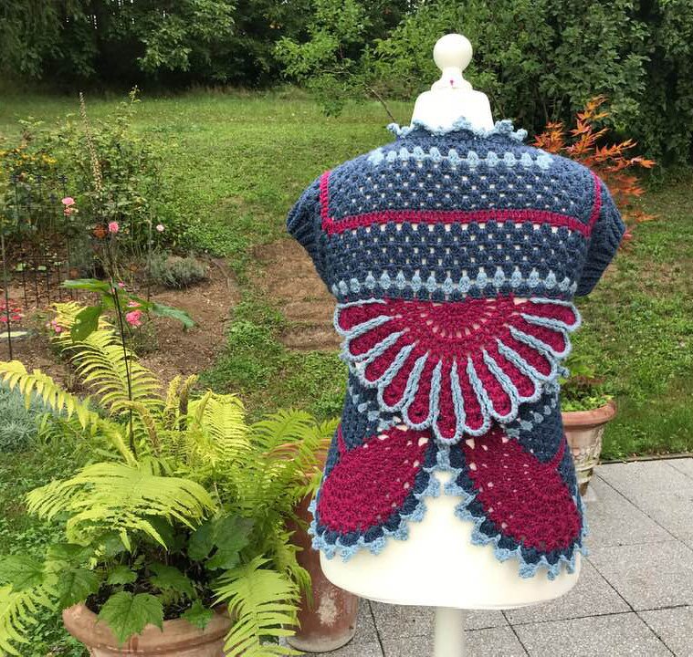 Rückenansicht einer mehrfarbigen Häkeljacke mit Muschel- und Fächermotiv sowie gezackter Saumkante