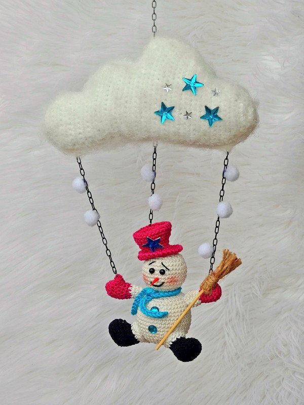 Gehäkeltes Wolken-Mobile mit blauen Sternen und hängendem Schneemann mit pinkem Hut