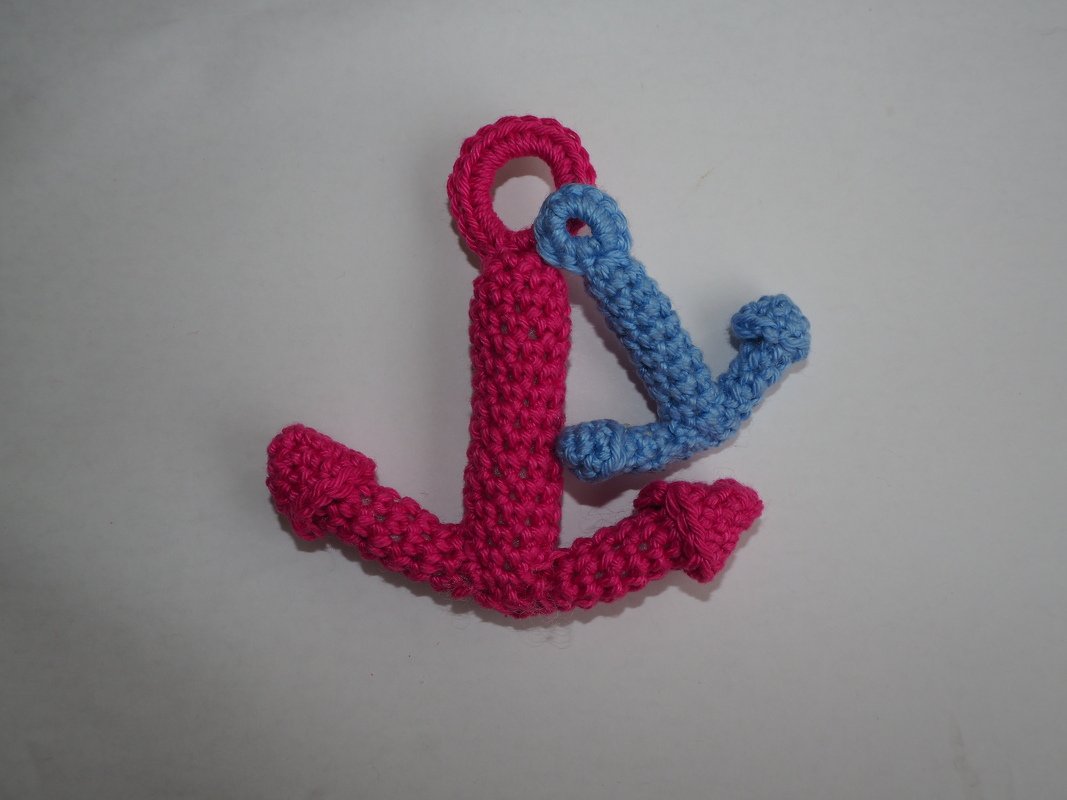 Zwei gehäkelte Anker-Schlüsselanhänger, einer pink größer, einer blau kleiner, auf hellem Hintergrund