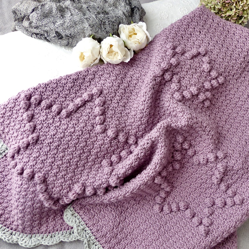 Handgehäkelte Babydecke in Lila mit Noppenstich-Herzen und grauem Wellenrand