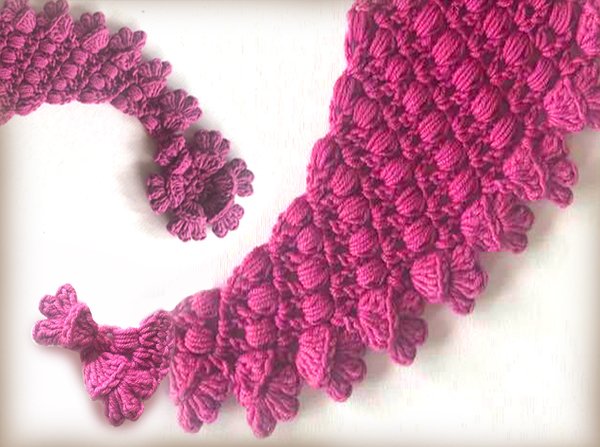 Nahaufnahme einer fuchsiafarbenen gehäkelten Rüsche mit Noppenstich und welligem Rand.