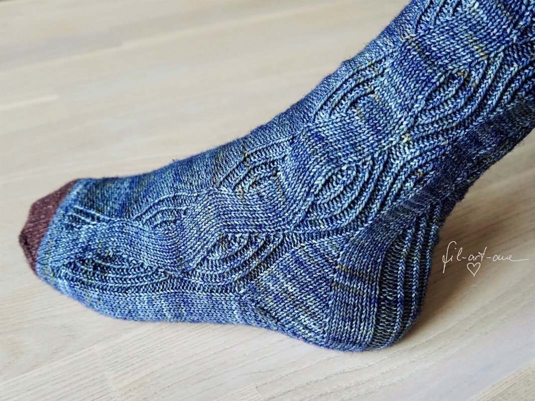 Blue variegated knitted sock with lace-cable pattern and contrasting brown toe