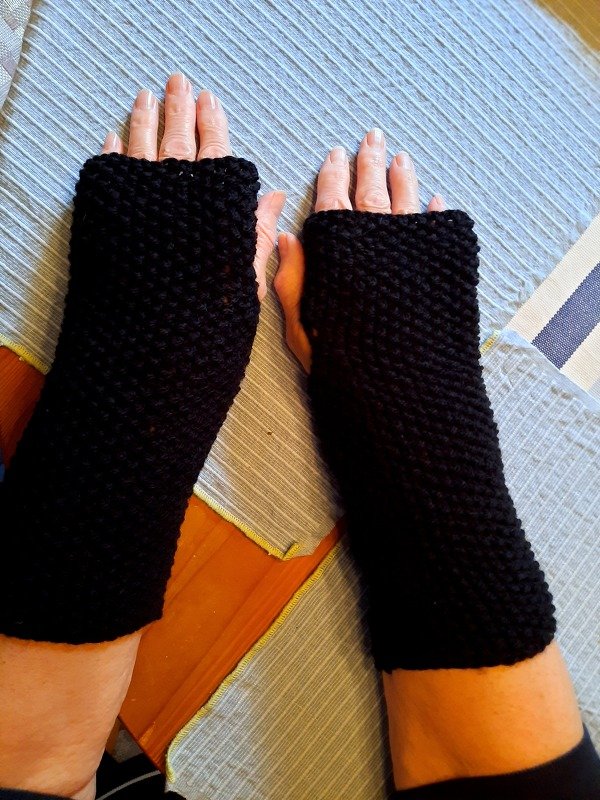 Nahaufnahme von Händen mit schwarzen gestrickten Armstulpen