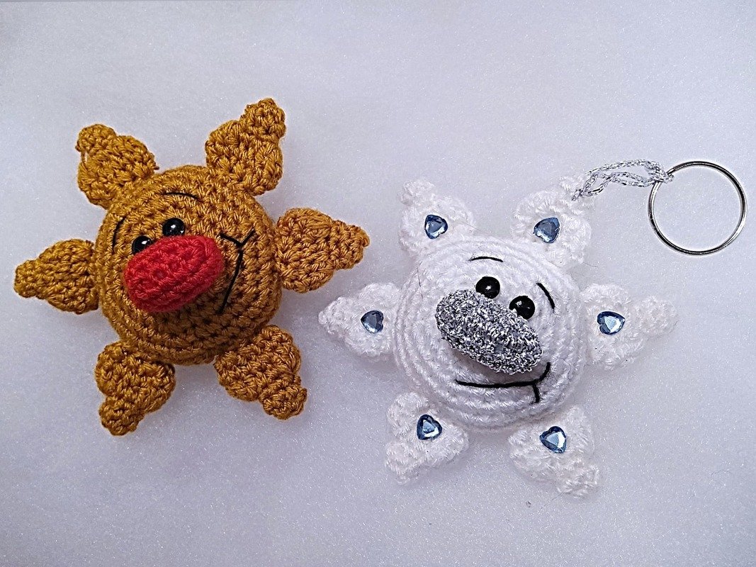 Zwei gehäkelte Anhänger: weiße Schneeflocke mit Strass und Metallring, goldbraune Weihnachtsfigur mit roter Nase