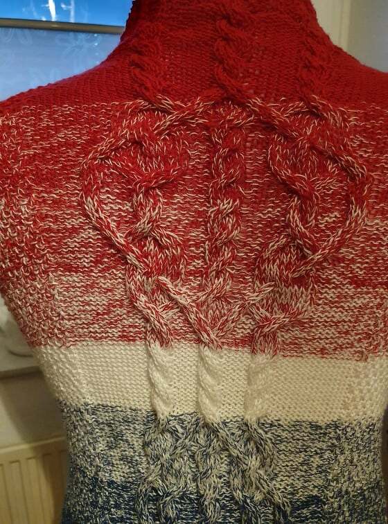 Rückendetail einer gestrickten Jacke mit herzförmigen Zöpfen und Farbverlauf