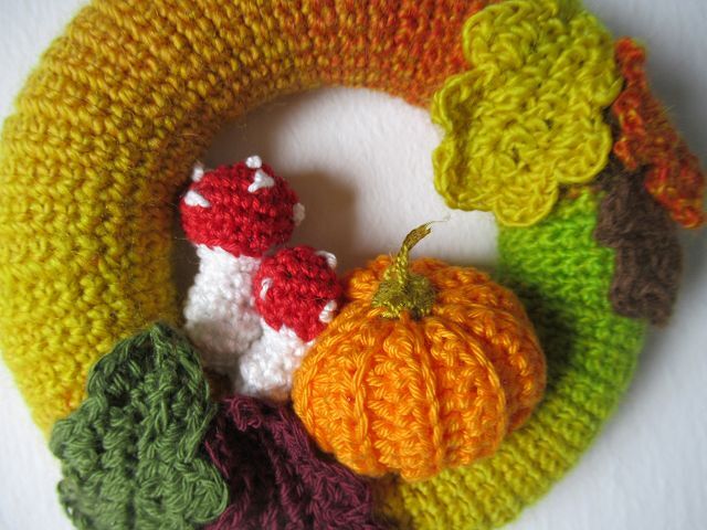 Gehäkelter Herbst-Türkranz mit orangem Kürbis, roten Pilzen mit weißen Punkten und mehrfarbigen Blattapplikationen auf einem gelb-grünen Ring