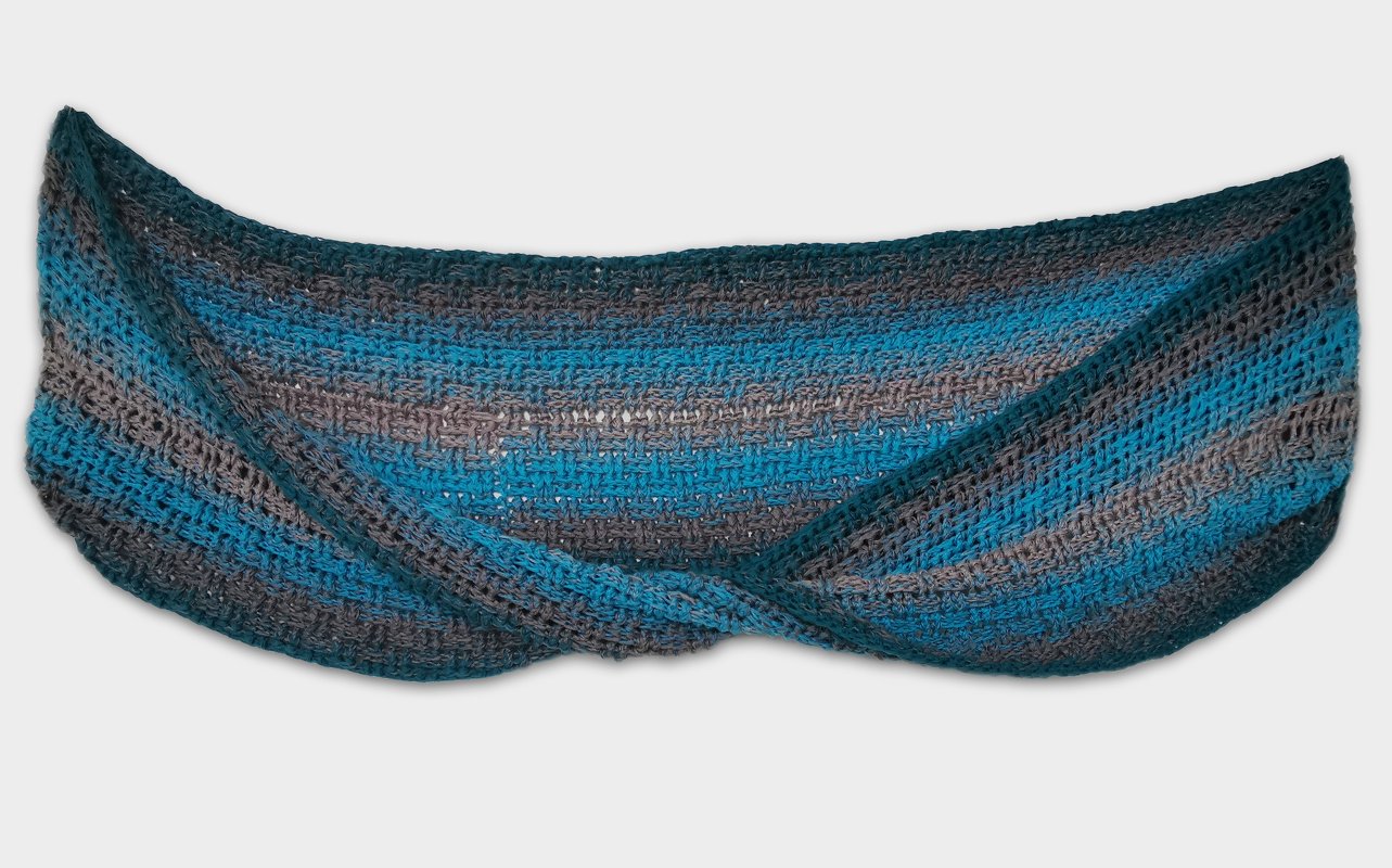 Flat-lay of a twisted crocheted cowl in teal and gray gradient stripes