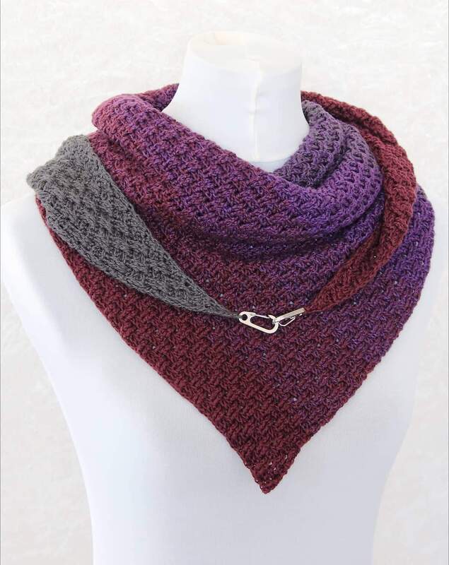Plum-to-gray triangle crochet shawl draped on a mannequin, fastened with a small metal clasp