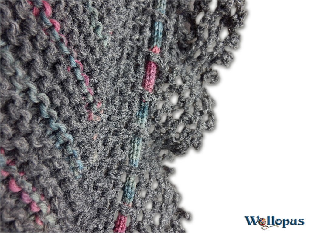 Nahaufnahme eines gestrickten Musters in Grau mit rosa und hellblauen Streifen und einem Lochrand.