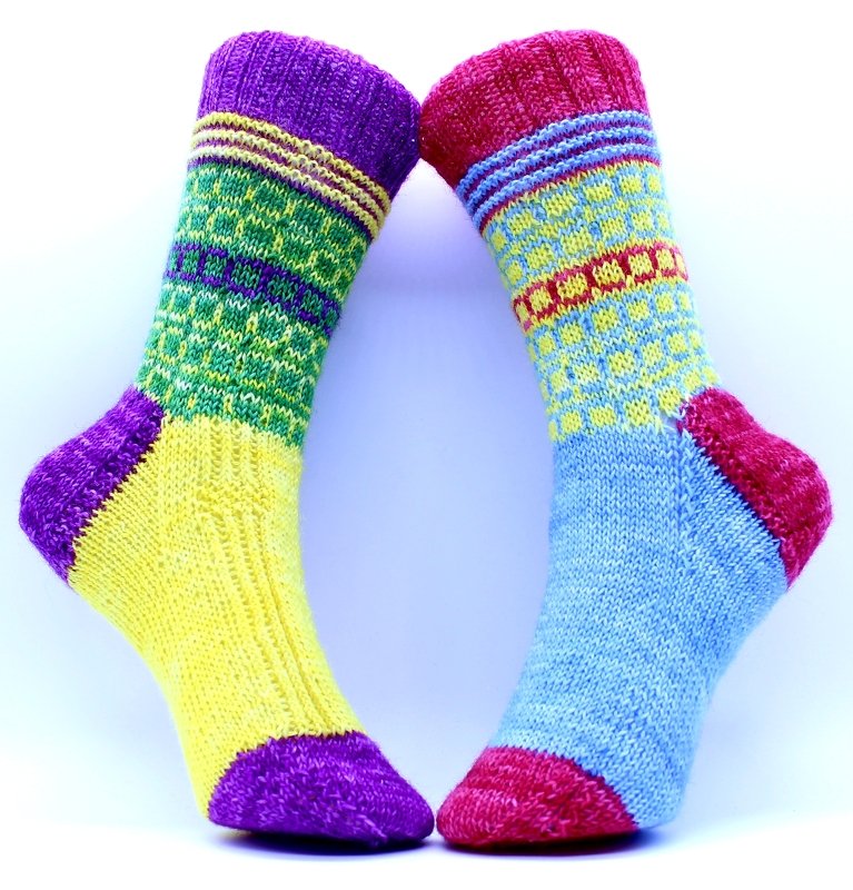 Zwei bunte gestrickte Socken mit gemusterten Bündchen, kontrastfarbener Ferse und Spitze
