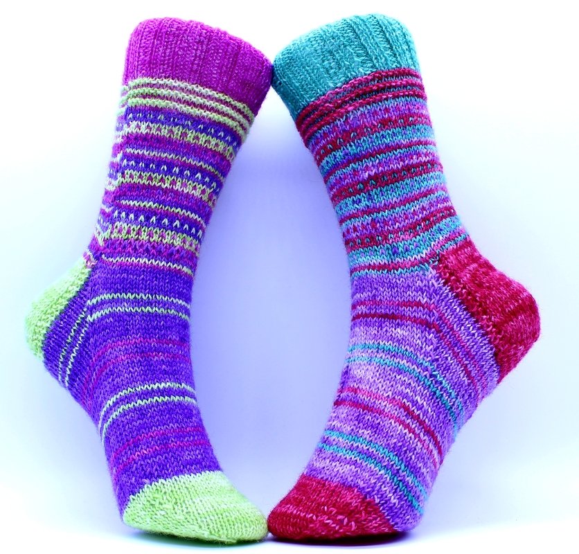Zwei bunte, handgestrickte Socken mit Ringeln und kontrastfarbener Ferse und Spitze