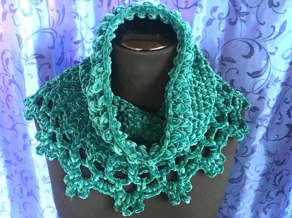 Tiefgrüner gehäkelter Rüschkragen auf schwarzer Schaufensterpuppe vor gemustertem Vorhang