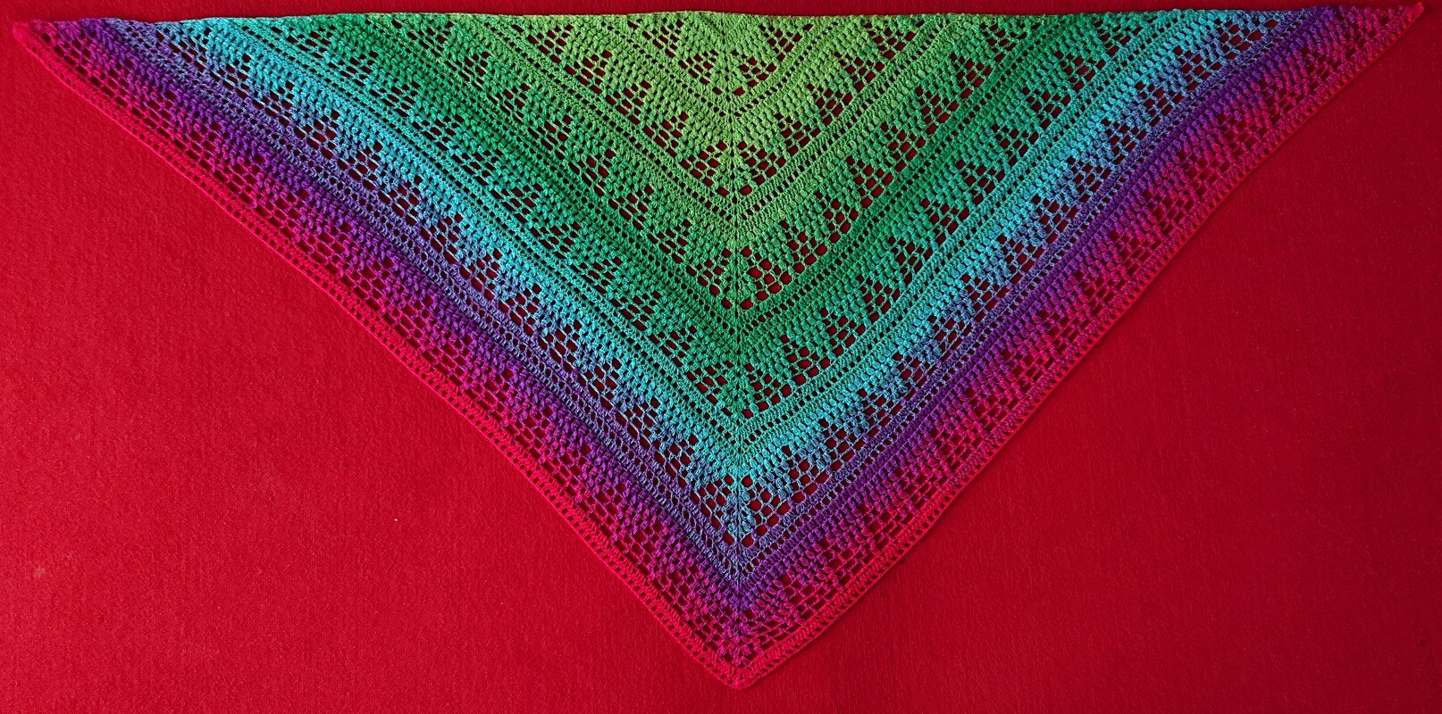 Buntes gehäkeltes Dreieckstuch mit Ajourmuster und Verlauf von Grün zu Pink