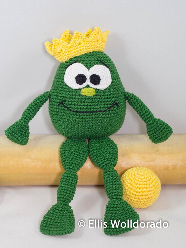 Grüner gehäkelter Amigurumi-Frosch mit gelber Krone und gelbem Ball
