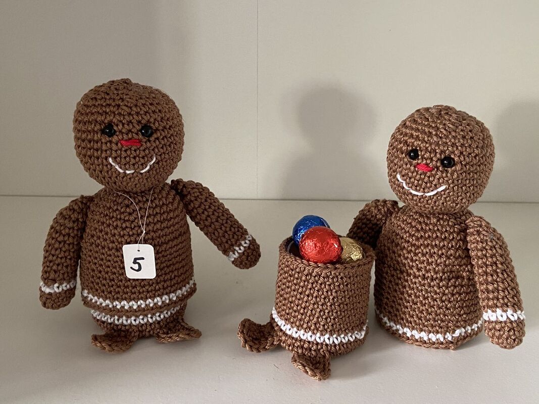 Zwei braune gehäkelte Lebkuchenfiguren mit weißen Details, Körbchen mit eingepackten Süßigkeiten und Zahlen-Anhänger „5“
