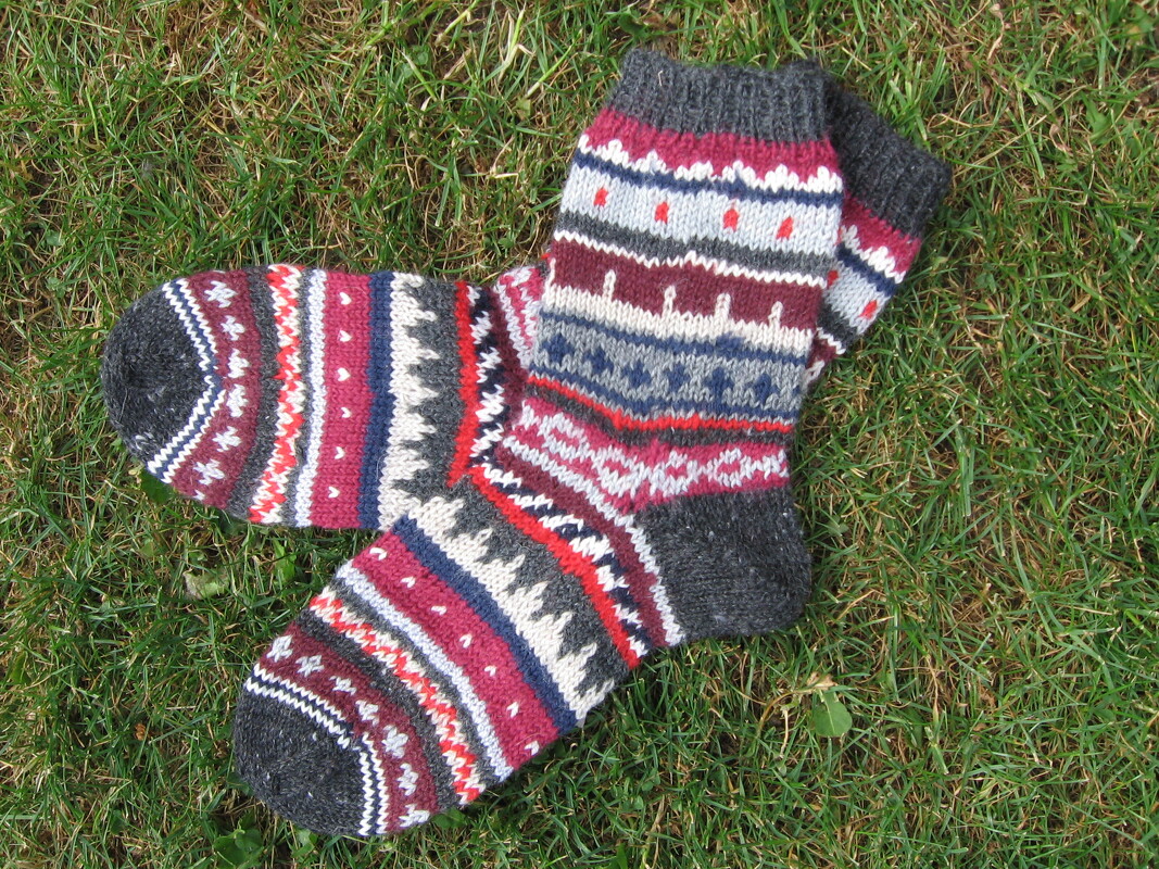 Mehrfarbige gestrickte Damensocken mit Norwegermuster auf Gras liegend