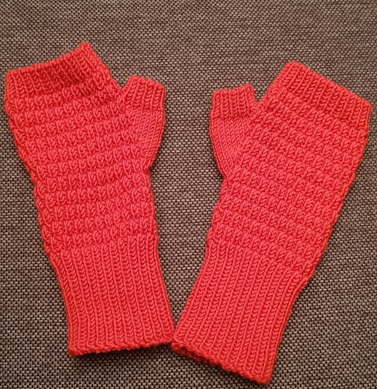 Paar korallenrote, gestrickte fingerlose Handstulpen mit Rippbündchen