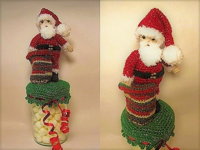 Gehäkelter Weihnachtsmann mit roter Mütze und Bart auf grünem Deckelbezug auf einem Glas mit Süßigkeiten.
