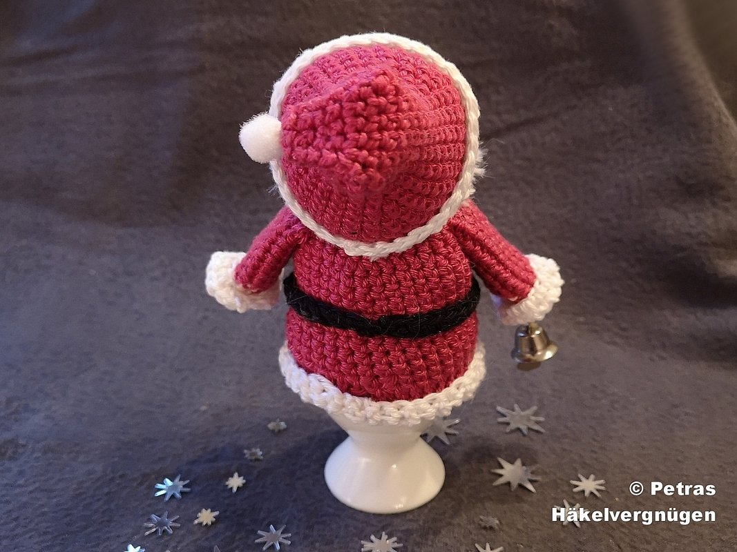 Gehäkelter Weihnachtsmann-Eierwärmer in Rot und Weiß auf Eierbecher, Rückansicht mit Glöckchen