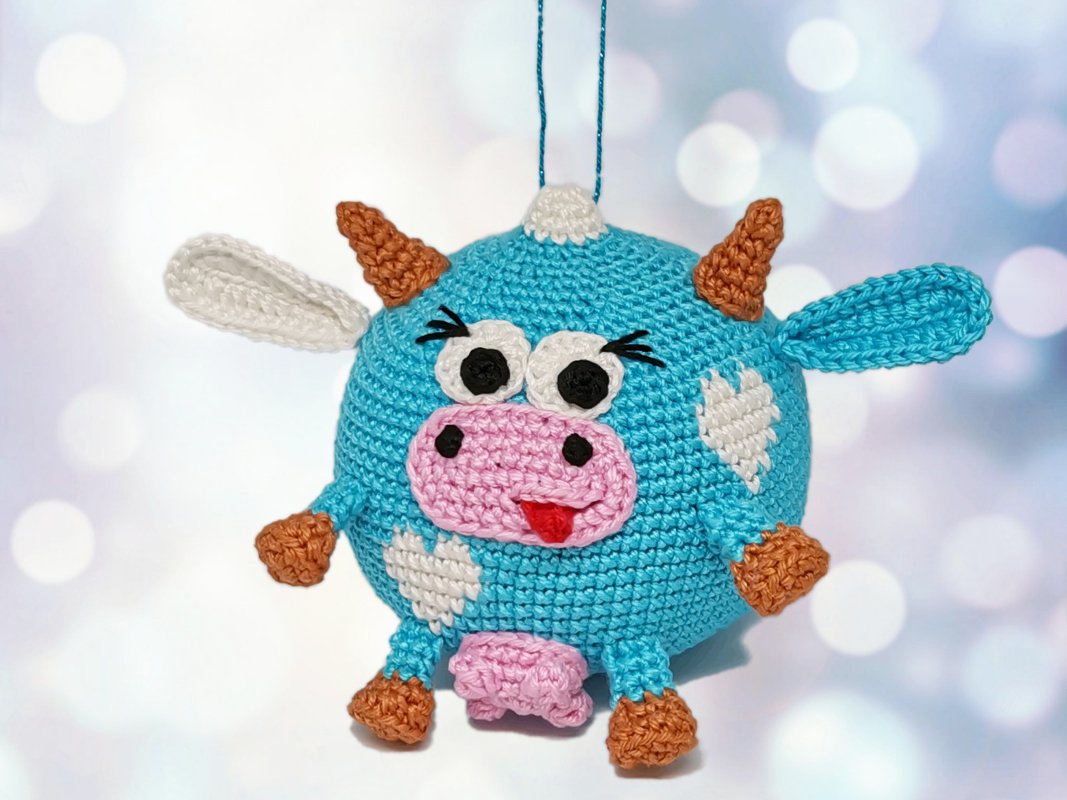 Whimsical turquoise crocheted cow ornament with pink muzzle, stitched white hearts and hanging loop