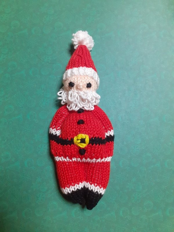 Gestrickter Weihnachtsmann auf grünem Hintergrund