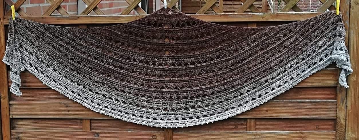 Crocheted crescent shawl in brown-to-grey ombre with openwork stitch pattern