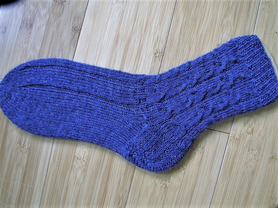 Violette Socke mit Rippenbund, Zopfmuster am Schaft und glatt gestricktem Fuß