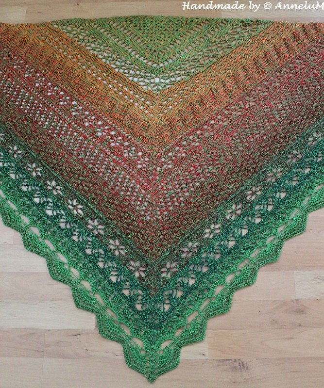 Crochet triangle shawl in green, orange and red gradient with floral openwork and scalloped edge.