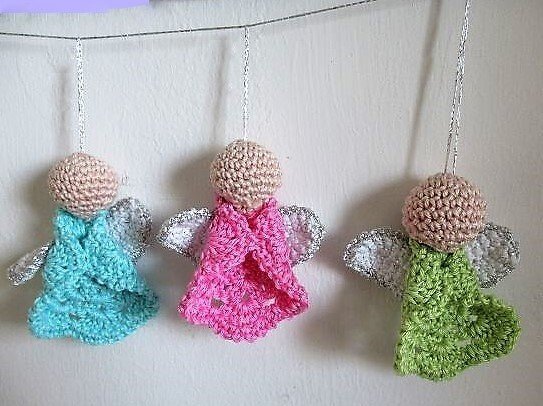 Drei gehäkelte Engel in Türkis, Pink und Grün mit funkelnden Flügeln an einer Schnur