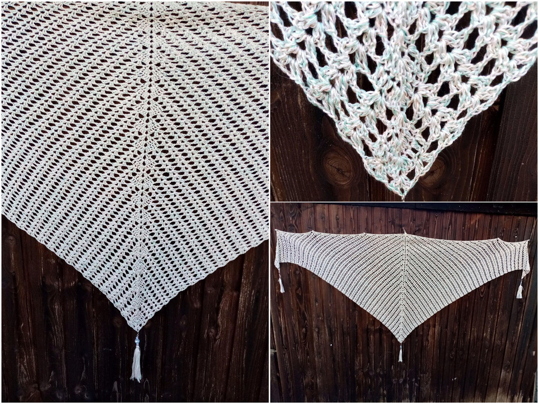 Hellfarbenes gehäkeltes Dreieckstuch mit Lochmuster und Quasten vor dunklem Holz